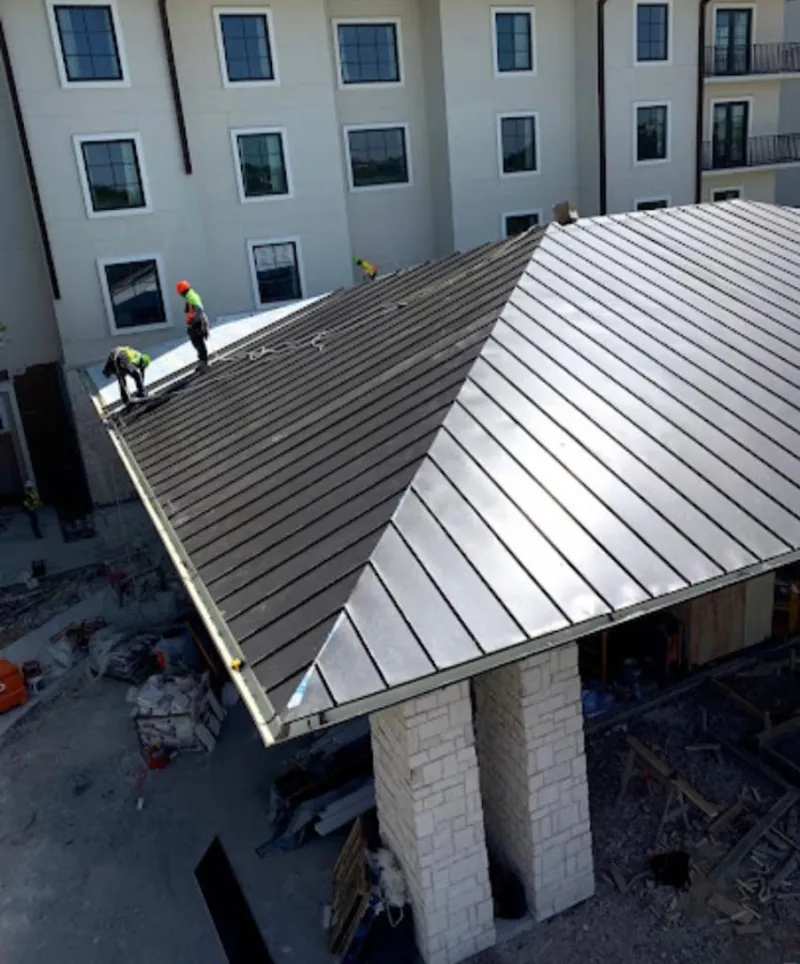 Crew installing standing seam metal roof panels on a commercial project in Venice